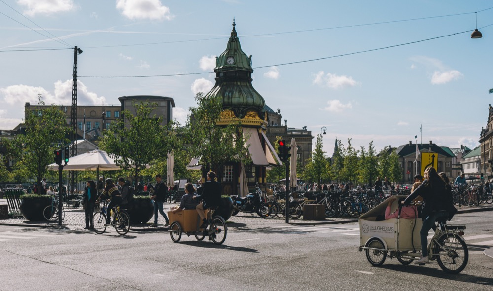 Cargo bikes crossing a square by the green clock kiosk