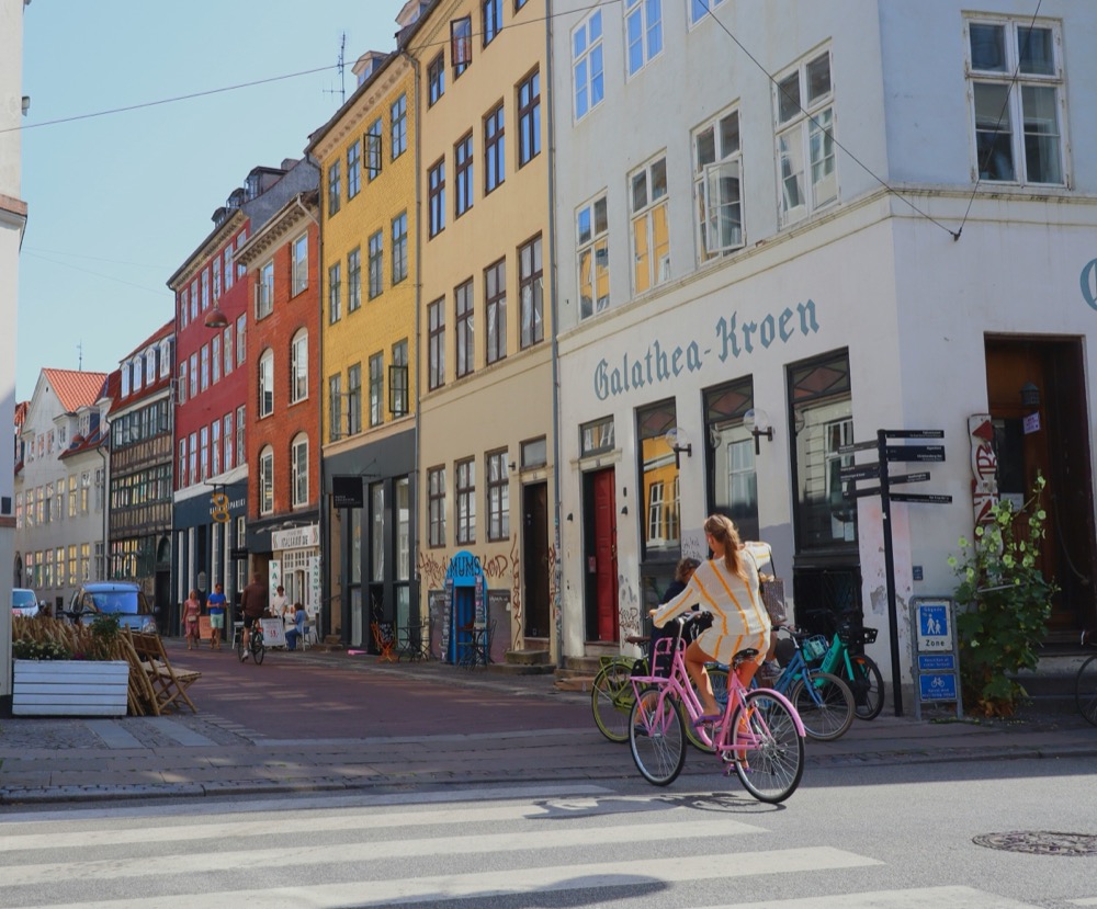 A cyclist on a pink bike passing colourful houses