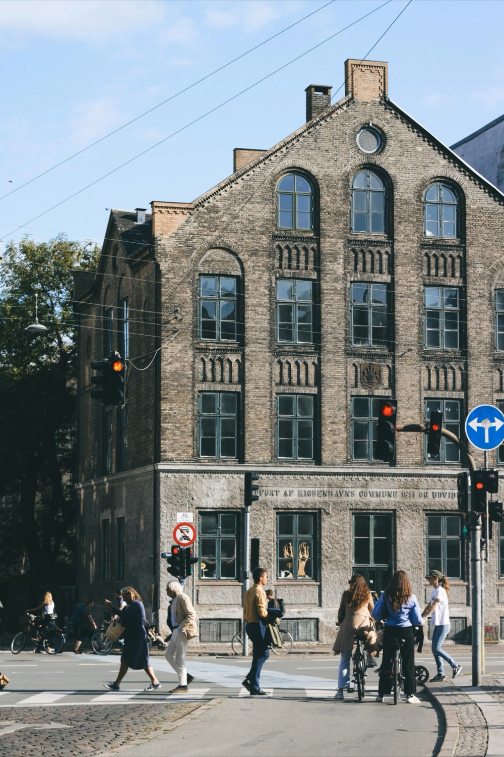 Cyclists and pedestrians at a crossing in front of a brick building