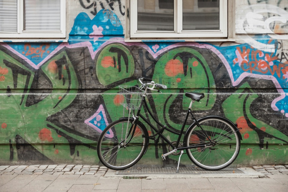 A black city bike leaning against a graffiti wall