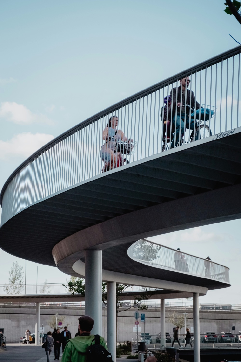 A family cycling over the spiralling Bicycle Snake bridge